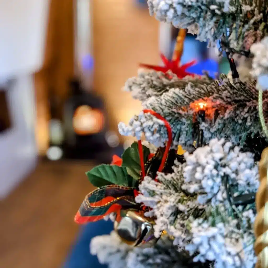 The Christmas tree on Kingfisher Narrowboat with hot tub sets the scene for romantic, Christmas hot tub breaks and a cosy lit log burner is seen in the distance. Magical winter canal holidays.