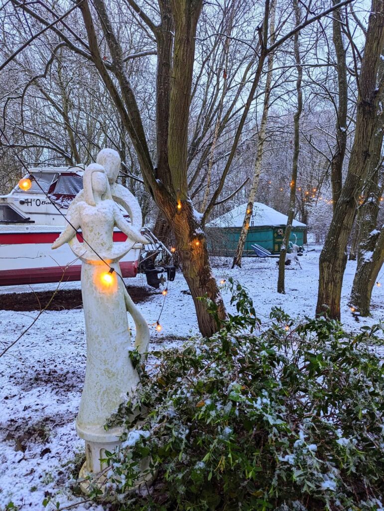 The woodland is covered in snow at Hawthorn Hideaway and the stone couple in an embrace greet you to the entrance of the woodland for romantic hot tub Christmas breaks.