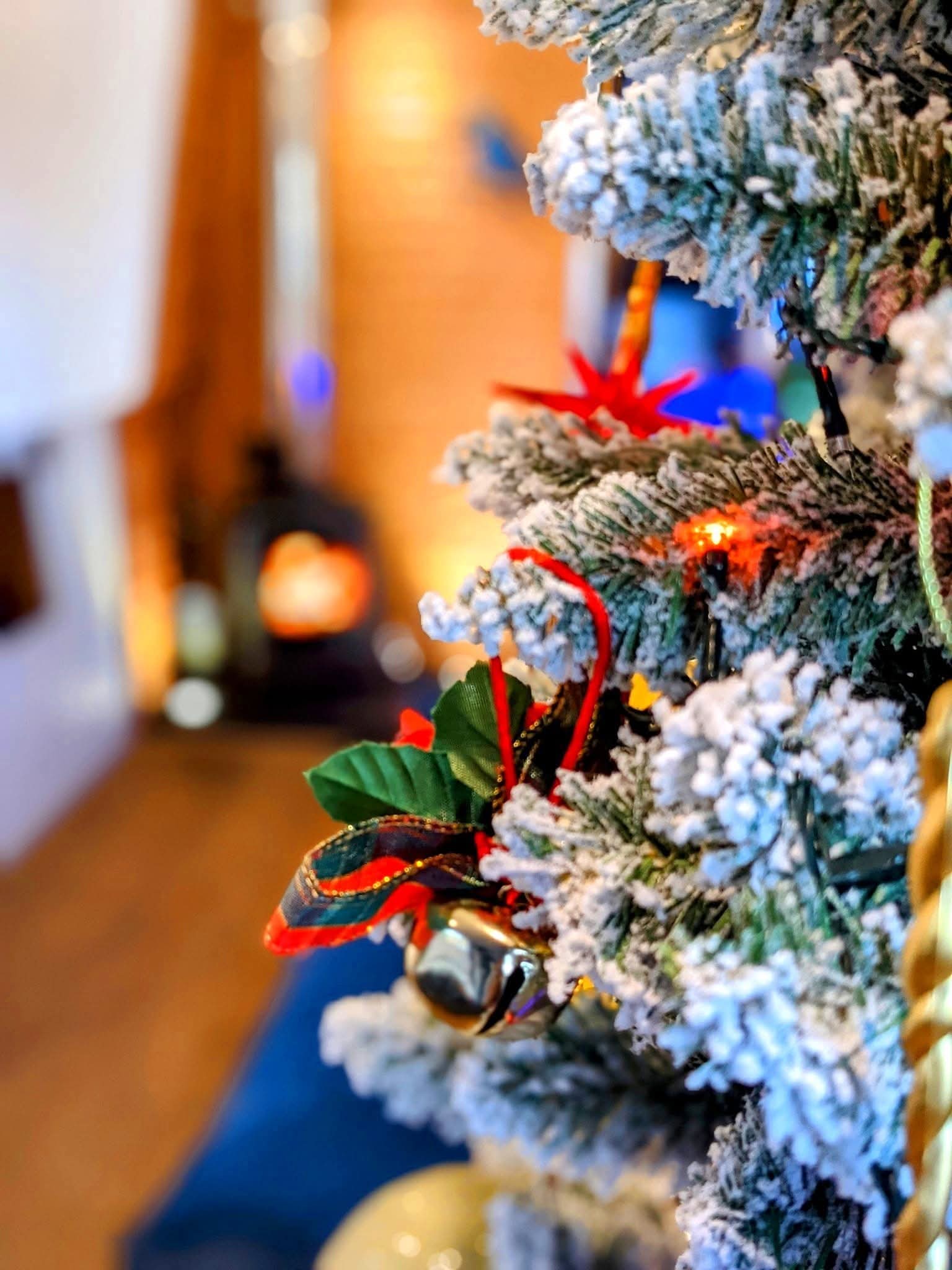 A canal boat winter stay with snow flake covered Christmas tree and a fiercely burning log burner in the distance.