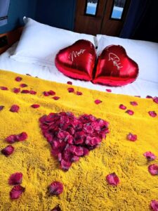 King-sized bed on the Kingfisher luxury narrowboat in Yorkshire decorated with rose petals and heart-shaped balloons , romantic canal boat with hot tub for couple