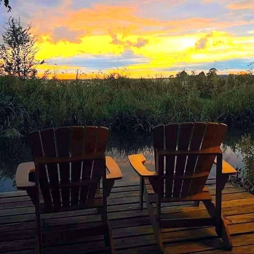 Two wooden chairs on the canal decking at sunset beside the Kingfisher luxury narrowboat in Yorkshire. Peaceful romantic escape on the Chesterfield Canal