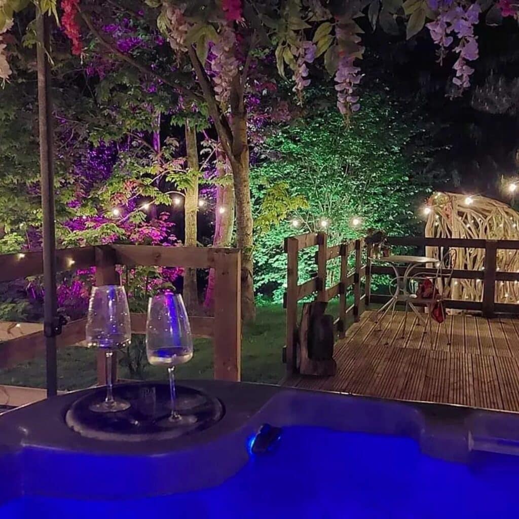 Private hot tub with drinks on Owl Lodge decking, with direct patio access and colourful woodland lighting.