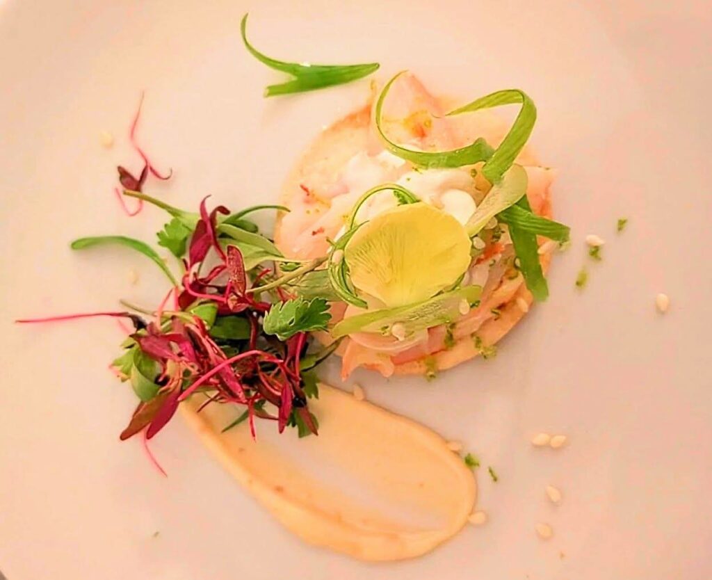 A delicately plated gourmet dish featuring tender protein, vibrant microgreens, edible flowers, and artful sauces, styled for an intimate, romantic private dining experience perfect for those romantic getaways, birthdays, anniversaries, proposals, weddings and honeymoons.