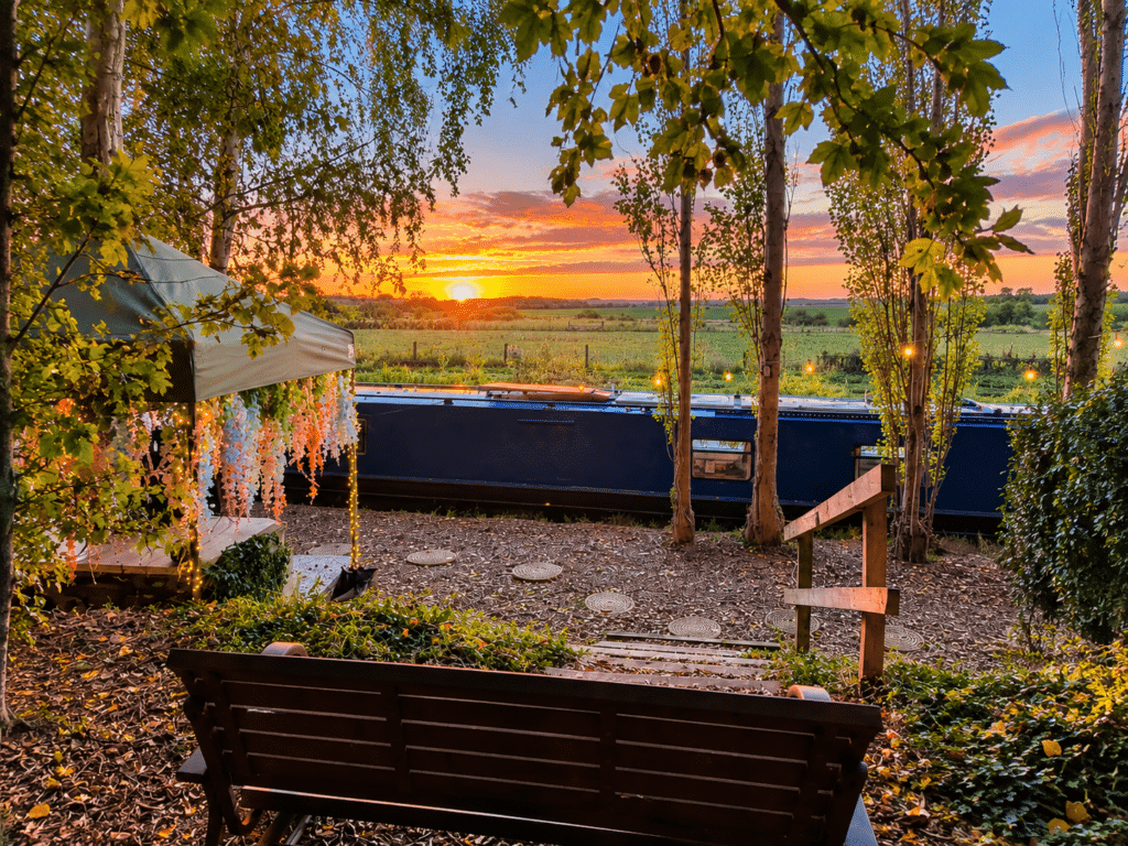 Sunset views over green countryside with raised seating adjacent to Kingfisher Narrowboat with hot tub for two.