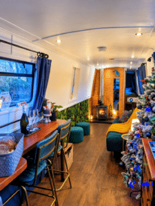 Kingfisher Narrowboat with cosy space with lit log burner, Christmas tree and a bottle of prosecco on ice.